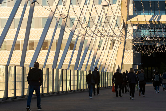 People pedestrian moving along bridge walkway in golden hour sunlight with modern urban architecture in Stockholm Sweden and calm rhythm