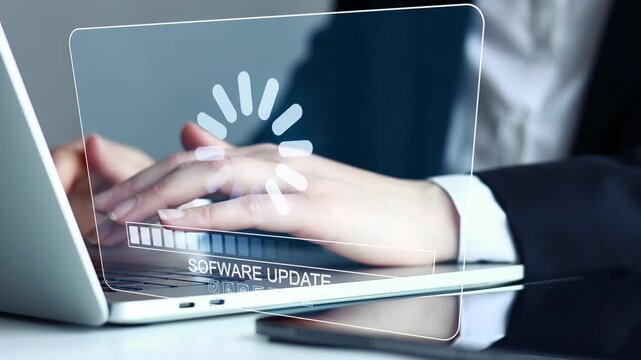 User performs software update on laptop while seated at desk in office environment during daytime.