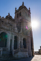 Obraz premium Facade of Porto Cathedral Se in Porto Portugal with arches stone columns and clock tower. Historic religious landmark with medieval architecture under clear blue sky.