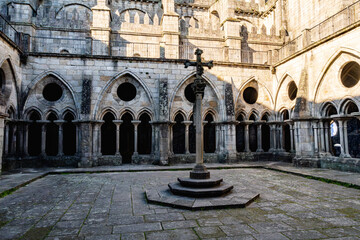 Obraz premium Historic cloister courtyard of Porto Cathedral with gothic arches and stone columns surrounding central cross monument. Ancient religious architecture in Portugal with peaceful atmosphere.