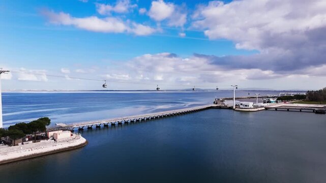 Aerial view of cable cars over Tagus river and waterfront under dramatic clouds. Lisbon, Portugal
