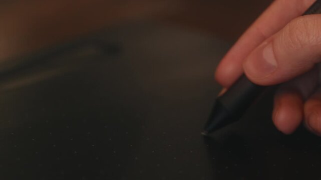 Macro cinematic shot of female digital artist hand holding stylus and drawing on black graphic tablet surface. Creative design process with selective focus on hand, warm light, blurred background.