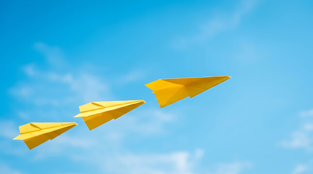 Yellow paper airplanes flying in the clear blue sky with clouds