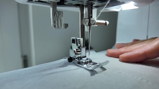 Close up of man sewing zigzag stitch on fabric with sewing machine. Tailoring process, garment repair and handmade textile work concept.