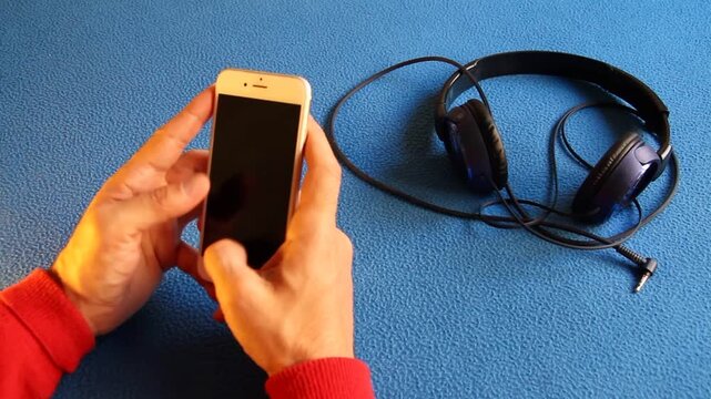 Usar tel&eacute;fono m&oacute;vil y chatear , escribir mensaje, contestar y enviar tecleando en pantalla smartphone celular en respuesta de conversaci&oacute;n y cascos de m&uacute;sica con fondo azul