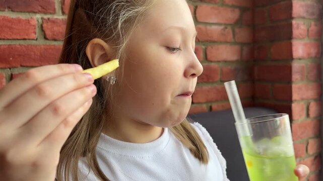 A schoolgirl in a cafe-restaurant is drinking lemonade with ice and tapioca balls.
