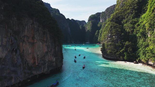 Stunning aerial view of traditional longtail boats, or Ruea Hang Yao, navigating the turquoise waters of Maya Bay on Koh Phi Phi Leh island in Thailand