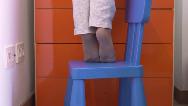 A little boy on tiptoe trying to reach something in his bedroom. Close-up of a child's feet on tiptoe.
