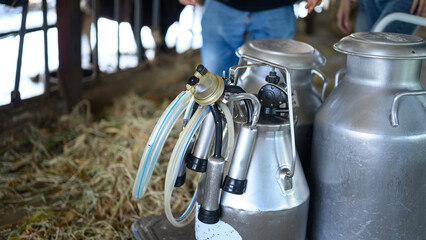 Dairy milking machine equipment and metal milk containers in farm barn © Prathankarnpap