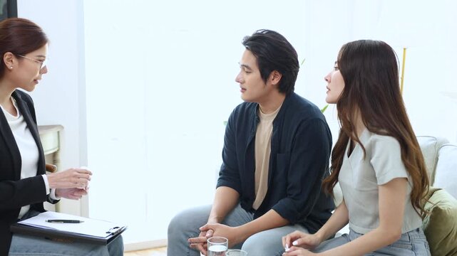 Asian couple sitting together with man expressing frustration during therapy session, dealing with work pressure and professional failure, seeking mental health support and relationship guidance