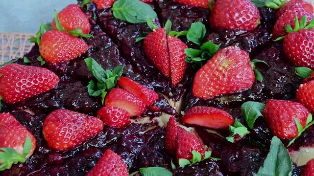 a freshly baked strawberry and plum tart, featuring a slow zoom-out that reveals the glossy red fruit glaze, fresh mint leaves, and sliced strawberries on a silver serving platter