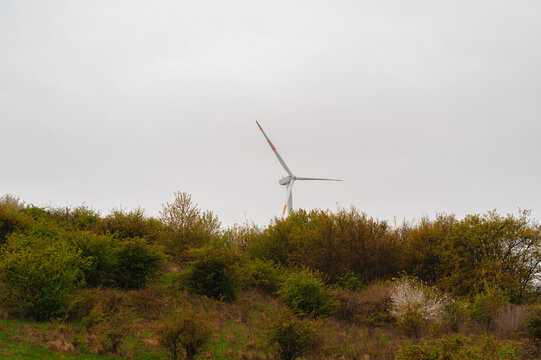Single Wind Turbine Above Scrubland Hills, Rising From Dense Low Shrubs Under Overcast Sky, Quiet Rural