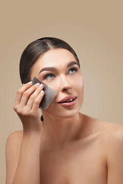 Young woman removing oil from face using blotting papers. Beautiful girl model with smooth and healthy skin. Skin care.
