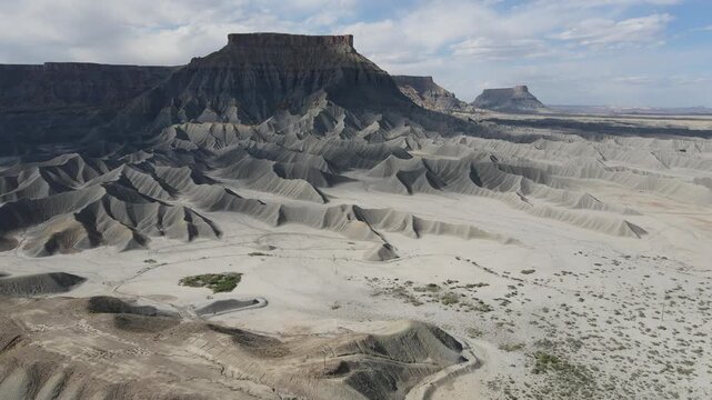 Stunning 4K drone footage featuring a smooth forward cinematic flight towards the majestic Factory Butte in Utah desert badlands. Shot at a high frame rate of 60fps for professional slow-motion use.
