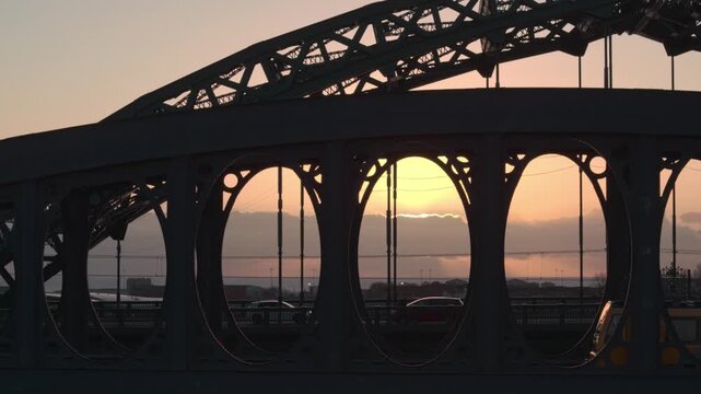 Aerial silhouetted shot of the Monkwearmouth Railway Bridge and Wearmouth Bridge at sunrise, featuring a Tyne and Wear Metro train crossing as the sun peeks through the industrial ironwork.