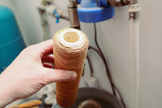 Dirty water filter cartridge being replaced in a home plumbing system