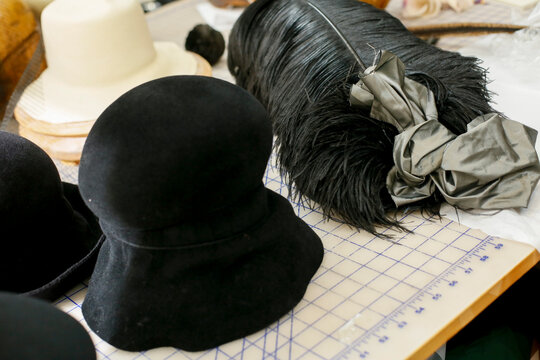 Unshaped felt hat body with feather trim on worktable