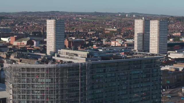 Aerial telephoto shot flying backward from Sunderland city center during morning rush hour, showcasing the urban landscape and high-rise architecture in the morning light.

