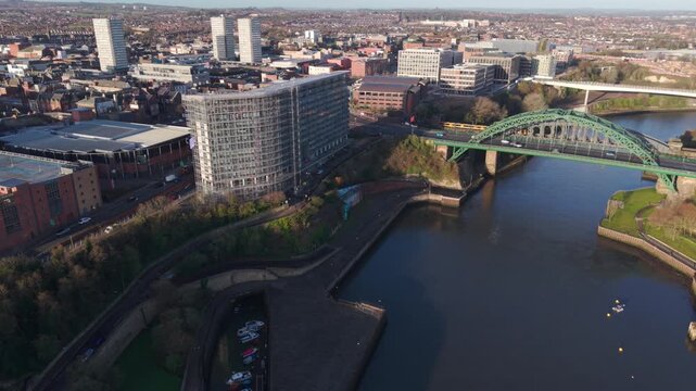 High-altitude aerial drone shot flying over the River Wear in Sunderland, revealing the Wearmouth Bridge and the modern city center skyline during a clear morning.
