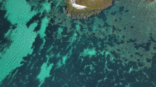 Aerial view of turquoise sea and rocky coastline clear water
