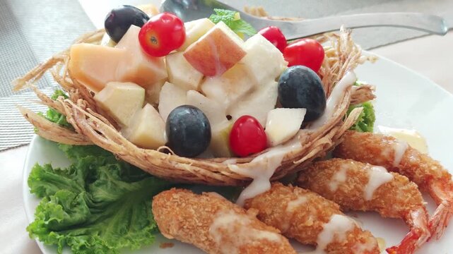 Fruit salad in a fried taro basket with shrimp.