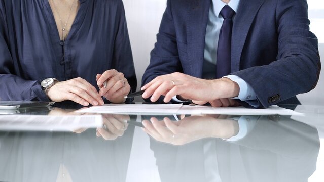 Business partners or lawyers are discussing contract papers during a meeting, negotiating and making decisions together. Business people concept, close up