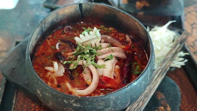 Pork noodle soup with meatballs served in a coconut shell bowl is a Thai dish.Noodle soup in a coconut shell bowl