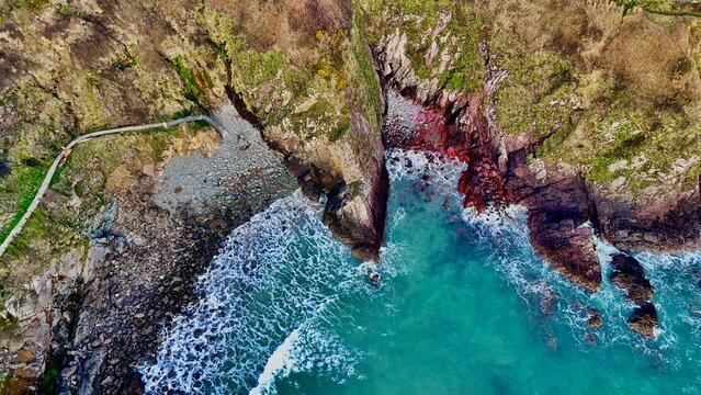 Top-down aerial drone view of Caerfai Beach with red rocks, Pembrokeshire, Wales with coast path