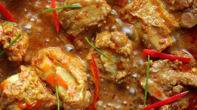 Stir-frying pork ribs with Thai red curry paste in a hot pan. Top view
