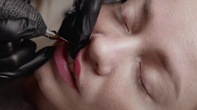 Tracking shot woman receiving lip tattooing and pigment application in beauty salon treatment, top view.