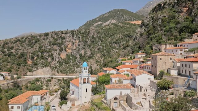 Stunning aerial view terrace cafe and historic hillside village of Dhermi in Albania. Traditional orange rooftop stone houses and iconic Holy Church of Saint Spyridon