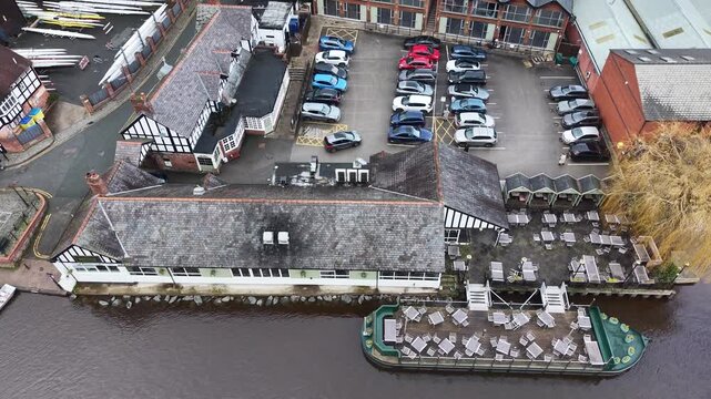 Aerial tilt up shot of The Boathouse pub with floating beer garden barge on the River Dee in Chester, riverside venue with outdoor seating and surrounding buildings England