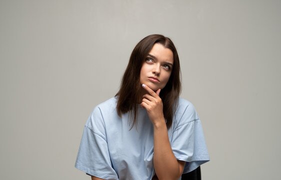 Young woman thinking deeply, looking up while contemplating a decision or new idea, problem solving