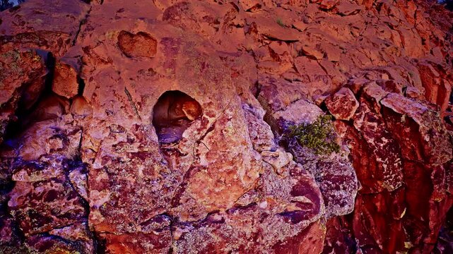 Drone shot flying high up rock face to peak inside small cave near summit