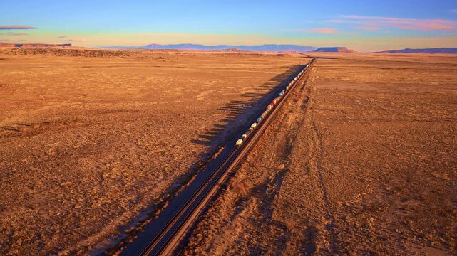 Cinematic drone shot of massive freight train traveling through a western landscape