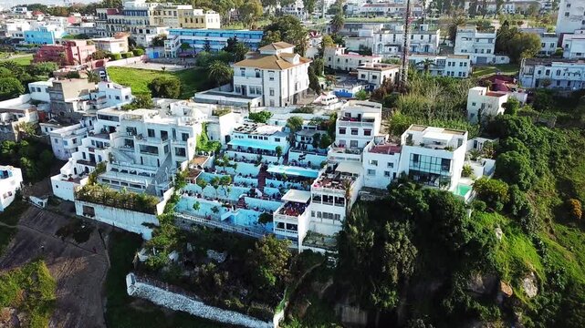 Cinematic drone shot of the iconic Cafe Hafa in Tangier, Morocco, featuring its famous terraces overlooking the Mediterranean Sea and the Spanish coast.
