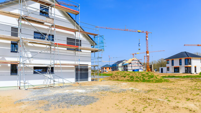 Construction site with new buildings and cranes in bright weather during day near residential area