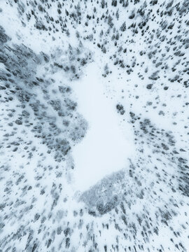 Aerial view of the Neitokainen pond shaped like the map of Finland surrounded by snow-covered coniferous forest in winter Kittila, Lapland, Finland.