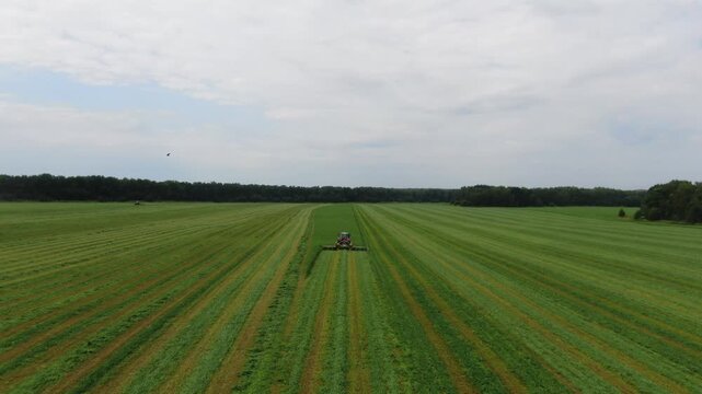 Drone following tractor mowing grass on field