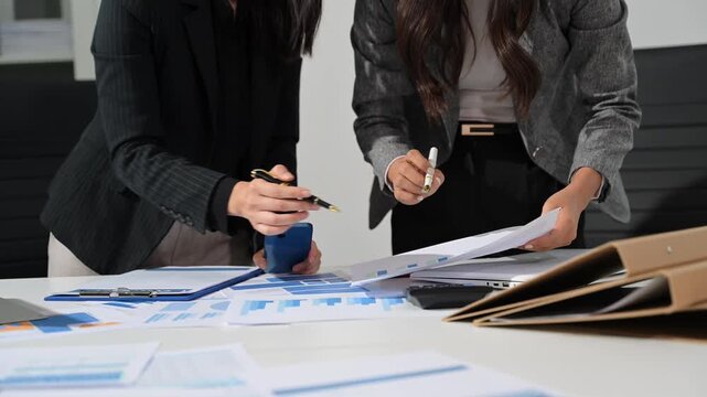 Businesswoman and team analyzing financial statement Finance task. with smart phone and laptop and tablet.