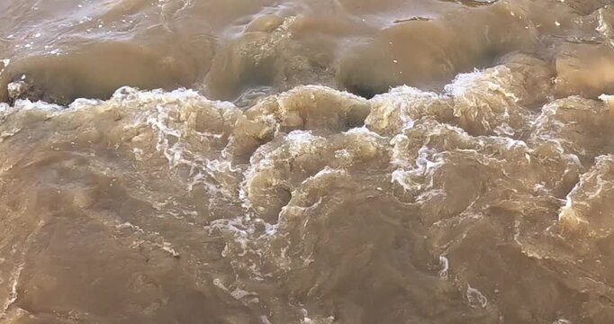 Turbulent, muddy brown water with white foam in Vantaanjoki river, Helsinki, Finland, Europe.