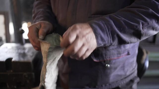 A worker puts on dirty gloves at a factory
