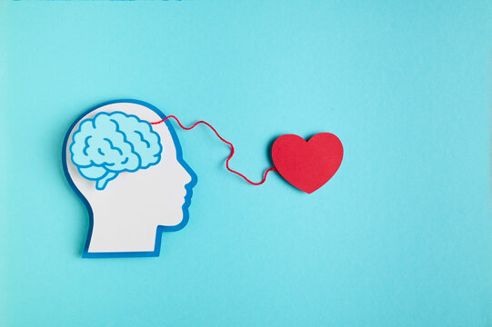 Silhouette of a human head with a brain against a blue background and a heart connnected to it