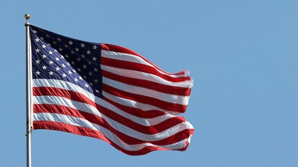 The American flag waves on a pole against a clear blue sky. US Memorial Day