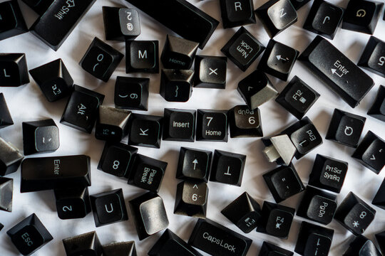 Broken computer keyboard with keys falling off on a white background.
