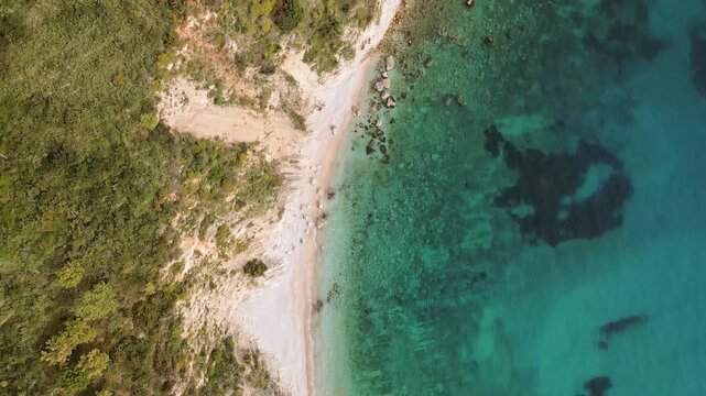 Aerial top down view pristine secluded non-commercialized Filikuri rocky beach.Clear turquoise Ionian sea meets steep rocky coastal cliffs. Scenic Albanian Riviera travel landscape in Himar&euml;, Albania.