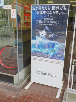 CHIBA, JAPAN - April 18, 2026: A poster advertising Softbank's Starlink Direct satellite service in front of a branch of Softbank inIchikawa City in Chiba Prefecture.