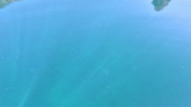 Water lake reflection showing mountain cliffs mirrored on the surface of turquoise blue water during a calm and sunny day