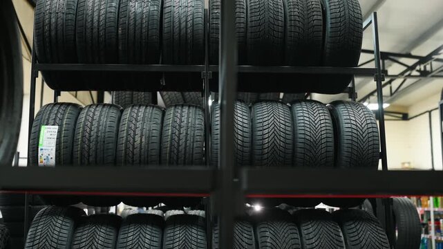 Black rubber tires are displayed on metal shelves in a tire storage facility, showcasing an organized and clean interior with industrial lighting