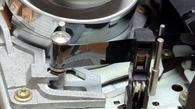 The internal gears and magnetic head of the VCR spin rapidly to read the VHS tape. This action creates a steady mechanical whirring sound and a faint, rhythmic hiss as the reels rotate.